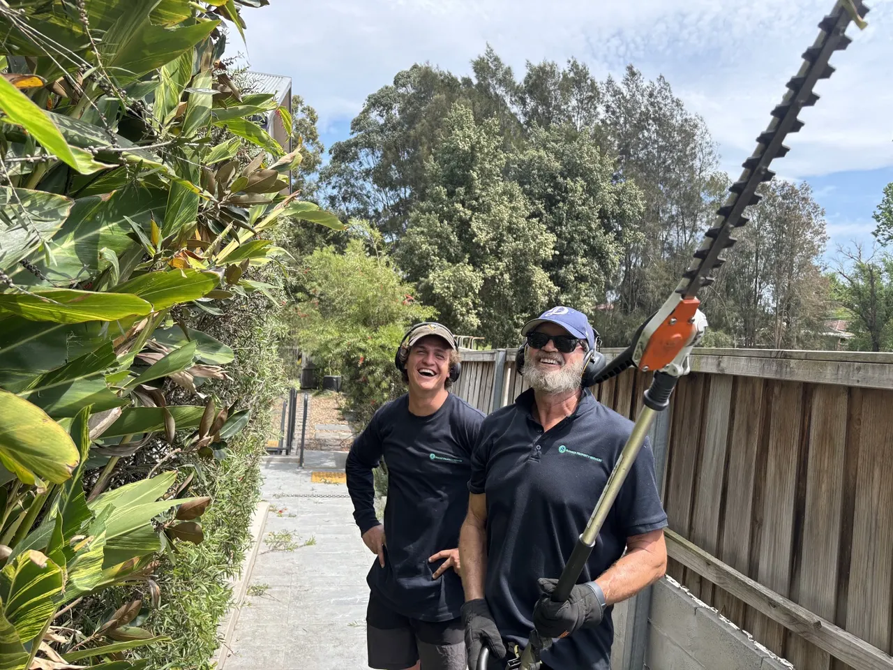 Two grounds team members carrying out hedge maintenance